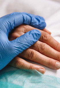 Hand van zorgpersoneel op hand van patiënt